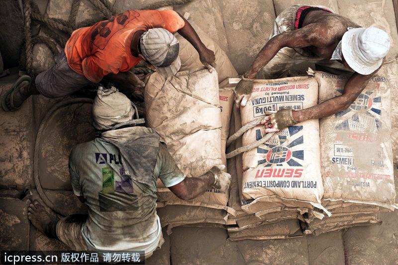 Los estibadores descargaban el barco llenado de bolsas de cemento 码头工人给装满水泥袋子的大船卸货。