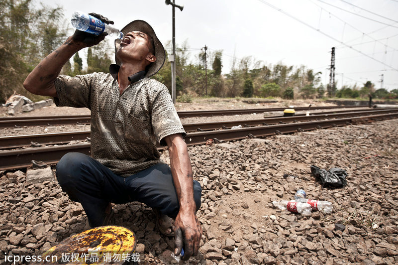 Un obrero estaba bebiendo al lado del ferrocarril 一名工人蹲在铁轨旁喝水。